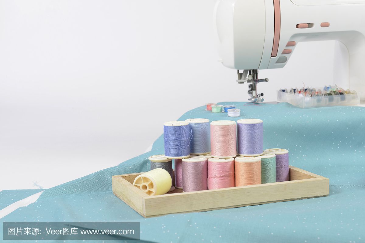 缝纫机和彩色线卷,剪刀,织物和配件,用于缝纫的白色背景,缝纫和针绣概念。(选择性聚焦)